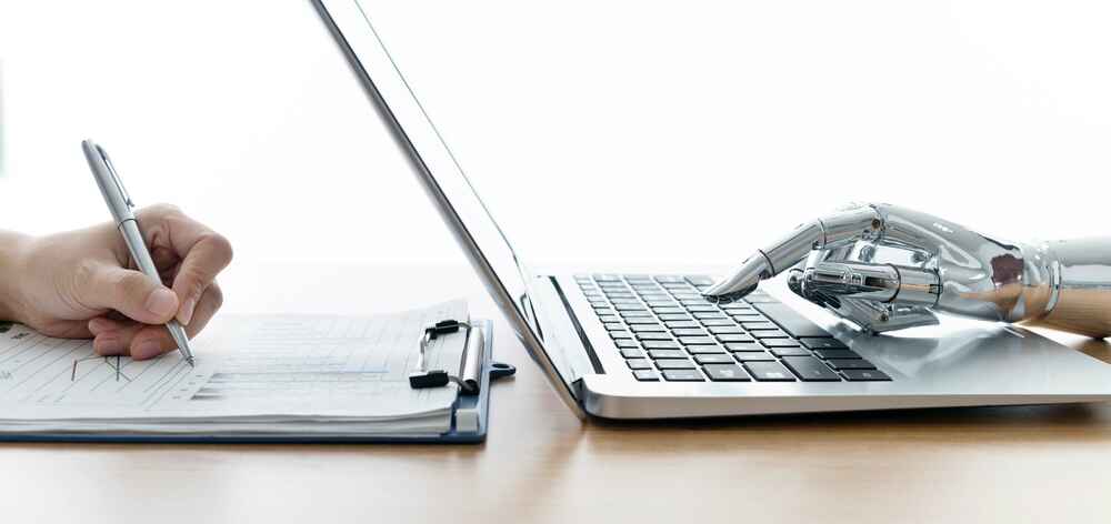 Robot hand using laptop and man hand writing stock photo