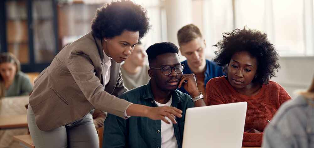 College students and their teacher use laptop during computer class