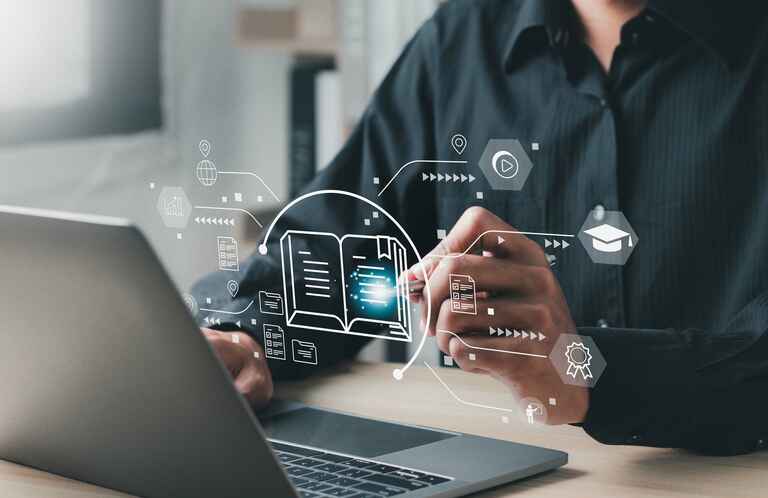 Close up photo of a person working on a laptop with educational technology images floating in the air