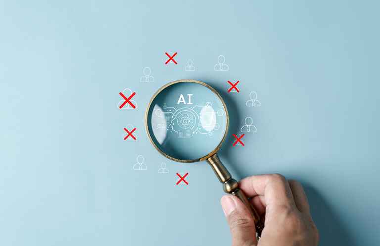 Image of a hand holding a magnifying glass over letters that spell AI