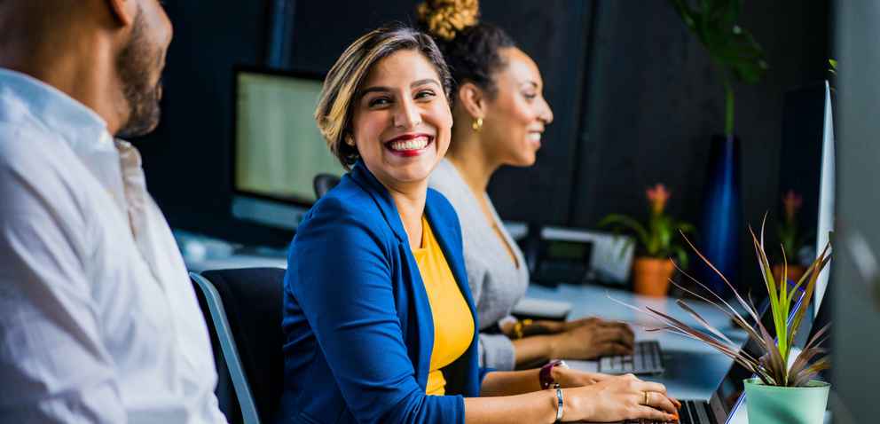 team of diverse coworkers laughing together at a workstation